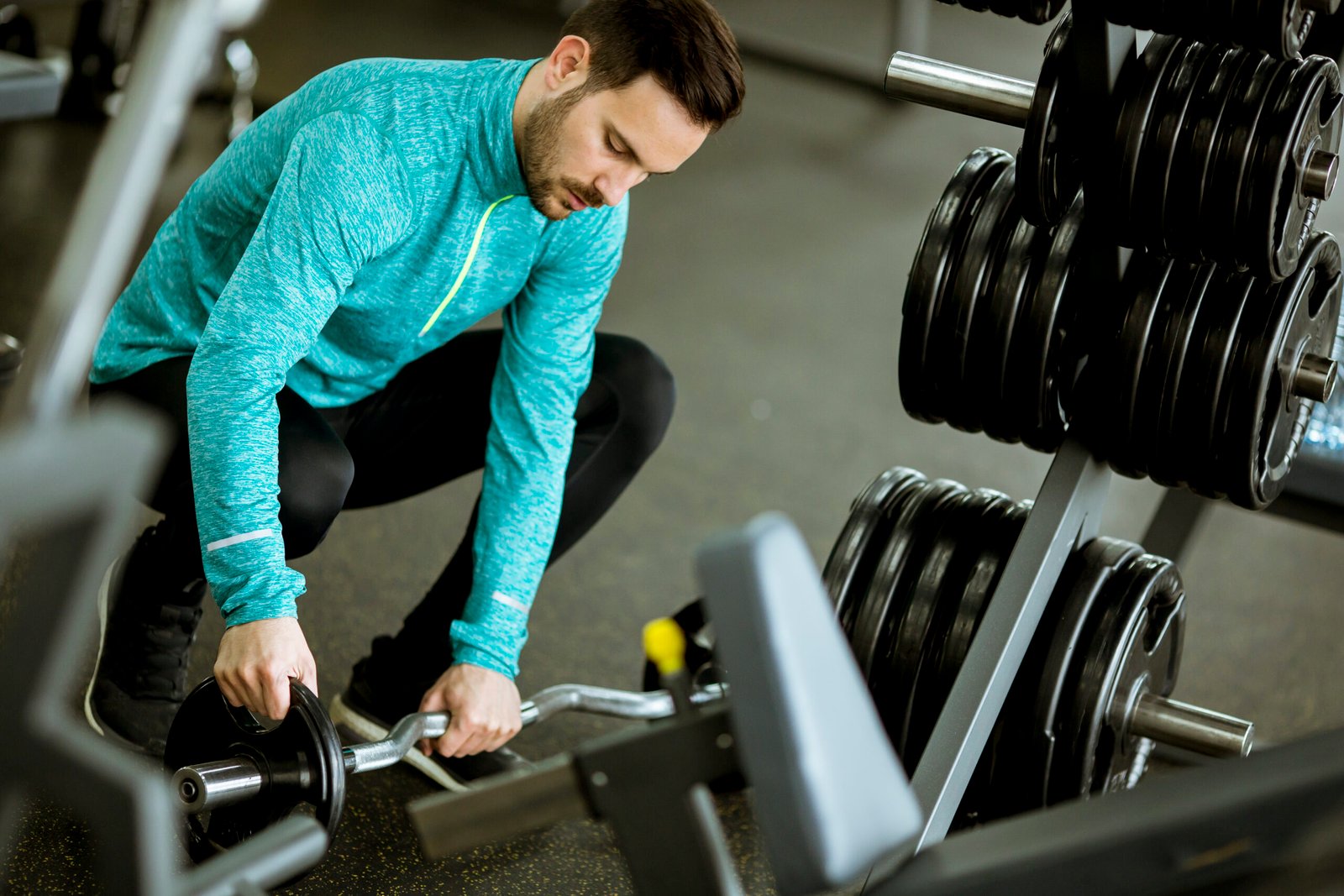Handsome young man preparing dumbbells in gym